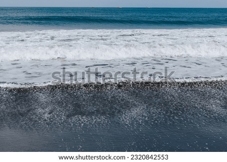 A textured sea wave washes the sandy beach. Beautiful natural background