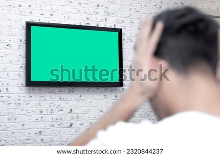 Shocked man on the couch watching tv. Bad news and Green screen concept	