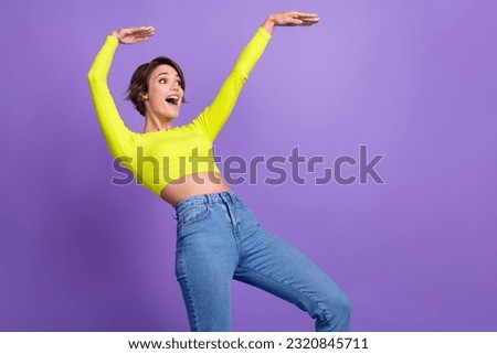 Photo of funky young girl fun dance listen music carefree good mood boogie woogie hands up look novelty isolated on purple color background