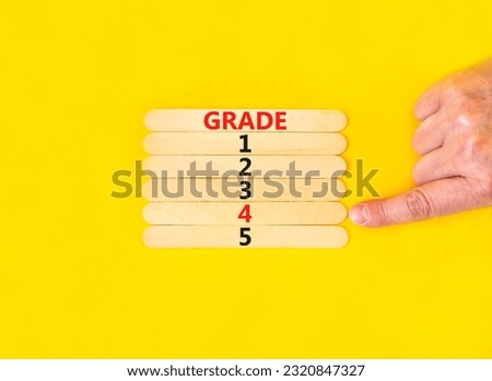 Time to grade 4 symbol. Concept word Grade 1 2 3 4 5 on wooden sticks. Businessman hand. Beautiful yellow table yellow background. Business planning and time to grade 4 concept. Copy space. Royalty-Free Stock Photo #2320847327