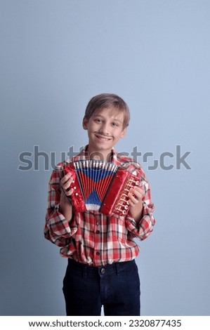 happy boy with harmonica at farm party in plaid outfit