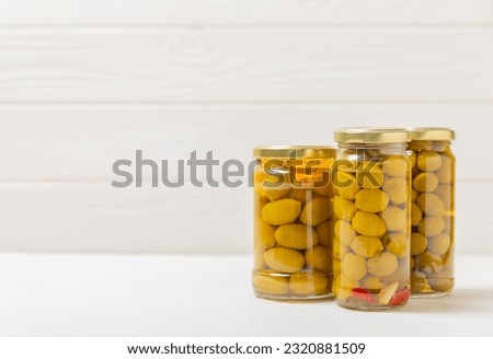 Pickled olives in glass jar. On a wooden background.Tasty olives on wooden table.Close-up.Place for text.Copy space. Delicious healthy mediterranean food.Vegan