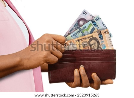fair Hand Holding brown Purse With Sierra Leonean Leone notes, hand removing money out of purse isolated on white background Royalty-Free Stock Photo #2320915263