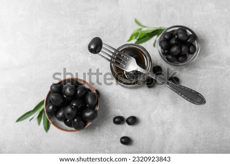 Pickled olives in glass jar on a light marble background.Tasty olives on wooden table.Close-up.Place for text.Copy space. Delicious healthy mediterranean food.Vegan.Olives in the kitchen