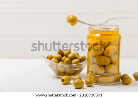 Pickled olives in glass jar. On a wooden background.Tasty olives on wooden table.Close-up.Place for text.Copy space. Delicious healthy mediterranean food.Vegan