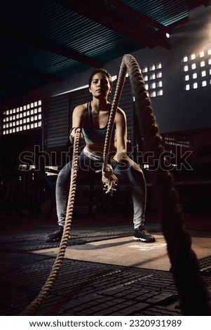 Woman training with battle rope in cross-training gym Royalty-Free Stock Photo #2320931989
