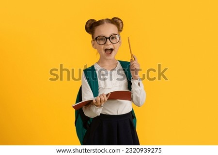Great Idea. Excited Cute Schoolgirl Holding Book And Pencil, Clever Little Female Child Ready To Answer A Question, Nerdy Pupil Girl Standing Isolated On Yellow Studio Background, Copy Space