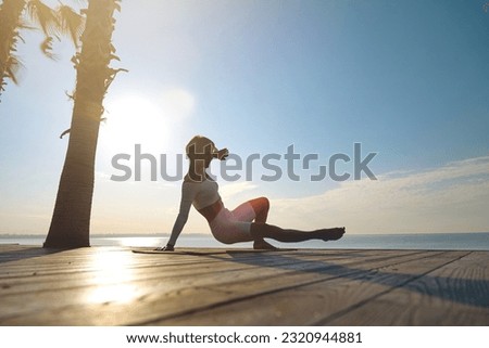 A woman is engaged in animal flow gymnastics outdoors near the sea on wooden floor. High quality photo Royalty-Free Stock Photo #2320944881