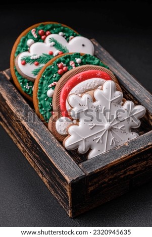 Delicious fresh colorful Christmas or New Year gingerbread cookies on a ceramic plate on a dark concrete background