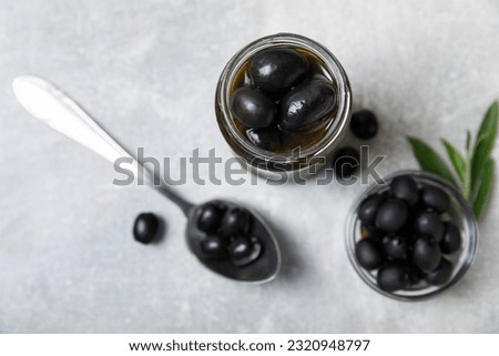 Pickled olives in glass jar on a light marble background.Tasty olives on wooden table.Close-up.Place for text.Copy space. Delicious healthy mediterranean food.Vegan.Olives in the kitchen