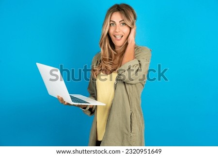Photo of amazed young beautiful blonde woman wearing overshirt holding modern gadget arm head