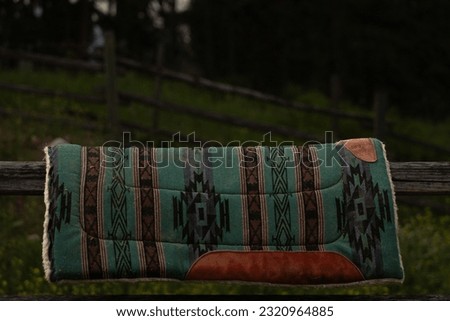 Green Western Saddle Pad with Dark Farm Background and Space for Text Royalty-Free Stock Photo #2320964885