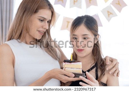 Image of excited happy pretty girls friends holding cake. Beautiful two girls blowing out the candle on a birthday cake. Holiday, happy friend and birthday concept.