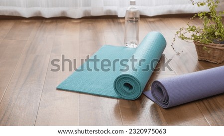 A rolled up yoga mat and water. Do yoga in the room. Royalty-Free Stock Photo #2320975063