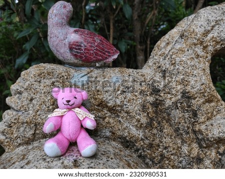 Pink mini panda doll sitting in decorative rock garden