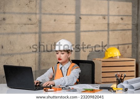engineer in helmet and vest civil worker smart young cute blonde girl working on computer
