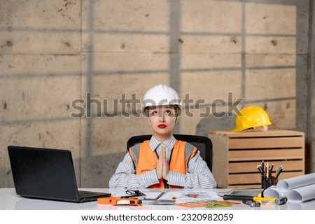 engineer in helmet and vest civil worker smart young cute blonde girl praying