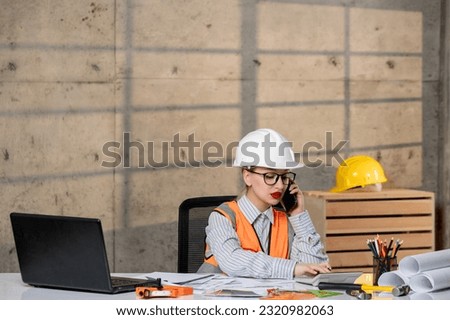 engineer in helmet and vest civil worker smart young cute blonde girl on phone call at work