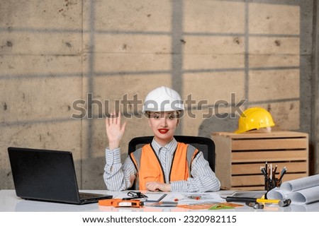 engineer young smart cute blonde girl civil worker in helmet and vest saying hello