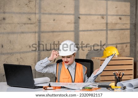 engineer young smart cute blonde girl civil worker in helmet and vest on laptop