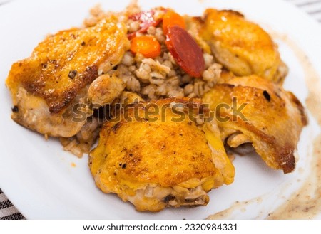 Closeup of tasty chicken thighs with pearl barley at plate on table