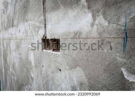 Hole in concrete wall, Unfinished electrical mains outlet socket without electrical wires - concrete wall, Home decoration, under construction building concept.