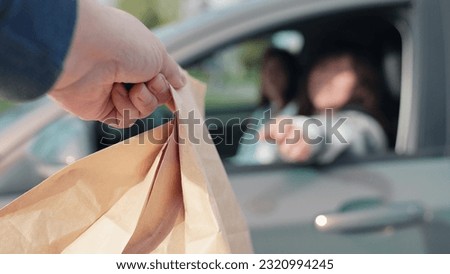 Fast food concept, delivery through auto window. Delicious meal, for travelers by auto. Woman driving, food delivery to car in package. Food for driver, passenger to eat on road. Buying food in car. Royalty-Free Stock Photo #2320994245
