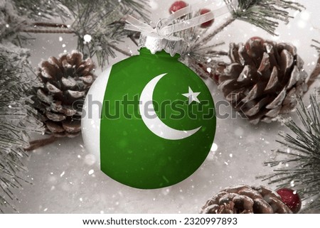 Christmas ball with the flag of Pakistan, decorates the snow tree with snowfall. The concept of the Christmas and New Year holiday
