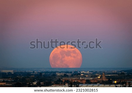 The strawberry Supermoon (Supermoon of strawberry) at sunset gradient from blue to pink on the city skyline in June 2020 in Spain. Royalty-Free Stock Photo #2321002815