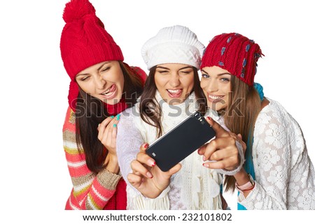 Friends making selfie. Three beautiful young women wearing warm winter clothing making selfie