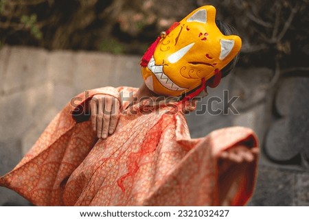 Japanese tradition and beauty: japanese blonde-haired woman in orange silk kimono with kitsune mask, bathed in morning sunlight at serene japanese park