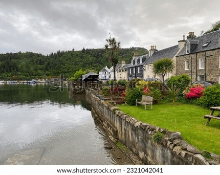 A view of the beautiful  small Scottish highlands town of Plockton, with flowers along the road, along the waters of Loch Carron,in  Scotland, United Kingdom Royalty-Free Stock Photo #2321042041