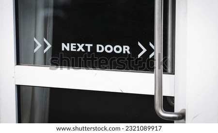 Next door sign written on a door of a modern building