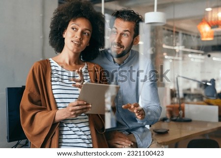 Smiling group of diverse businesspeople going over paperwork together, working in corporate office Royalty-Free Stock Photo #2321100423