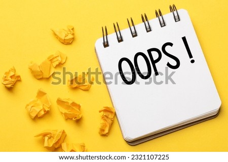 The words Oops with a black marker in a notebook on a yellow background .. Apologies for a minor accident or mistake.