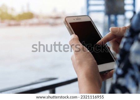 Close up hands of woman standing at a boat station. She talking to someone on her smart phone. Public transportation and urban life concept.