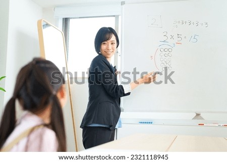 A woman in a suit teaching a child Royalty-Free Stock Photo #2321118945