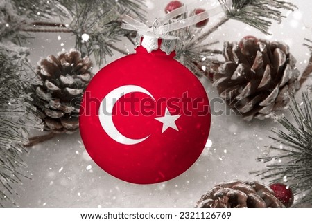 Christmas ball with the flag of Türkiye (Turkey), decorates the snow tree with snowfall. The concept of the Christmas and New Year holiday