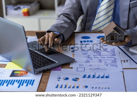Businessman holding pen pointing to market graph and working on laptop computer working using calculator for mathematics on wooden table at office finance concept close up pictures