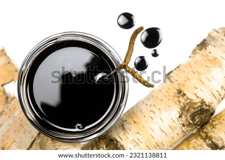 Birch tar or pitch in a jar and birch tree bark on white background. Wood tar. Liquid mineral tar from birch bark Royalty-Free Stock Photo #2321138811