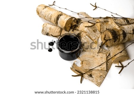 Birch tar or pitch in a jar and birch tree bark on white background. Wood tar. Liquid mineral tar from birch bark Royalty-Free Stock Photo #2321138815