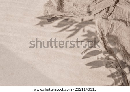 Neutral beige ceramic stone tabletop texture background with crumpled linen fabric an and aesthetic floral sunlight shadow. Minimalist business brand template, frame with copy space