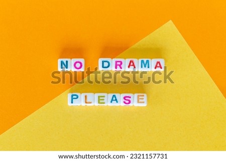 Phrase No drama please made out of square beads on orange and yellow background, flat lay. High quality photo.