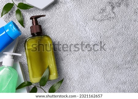 Different face cleansing products and green leaves on white textured table, flat lay. Space for text
