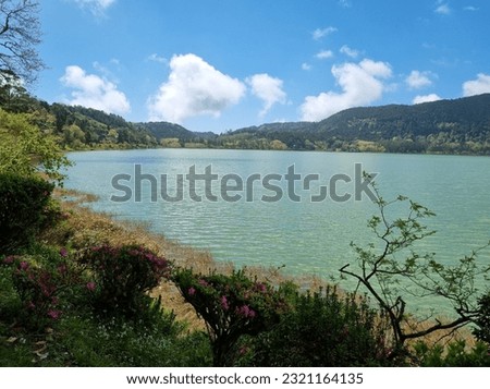 Beautiful view of Furnas Lake "Lagoa das Furnas" in São Miguel Island - Azores - Portugal on a bright sunny day, Peaceful lake with bright emerald water under blue sky