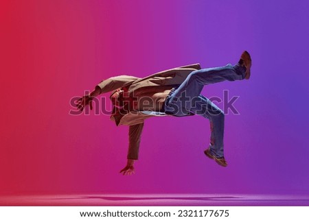Dance show. Young guy in stylish clothes dancing hip hop, breakdance, contemp against pink purple studio background. Concept of art, street style dance, fashion, youth, hobby, dynamics, ad Royalty-Free Stock Photo #2321177675