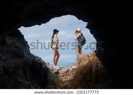 Couple asian teenage female travel island take photo camera. view from cave hole clear sky 
