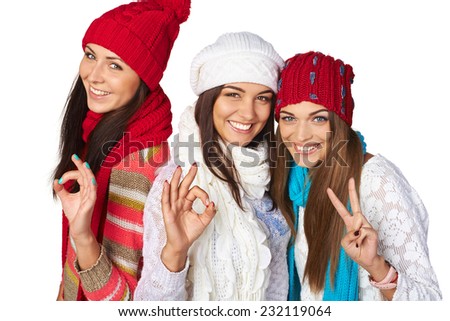 Three success girls wearing warm winter clothing showing approving gestures, over white background