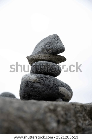 Vertical image. Green and gray stones in a beautiful balanced stack ona rocky Massachusetts New England shoreline, focus meditation background concepts