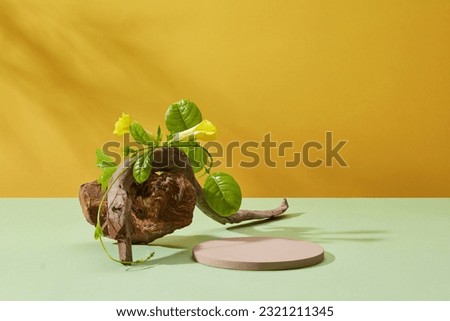 Gray podium in round-shaped displayed with tree branch, stone and a plant. Yellow background with tropical leaves shadow. Stage showcase on minimal podium